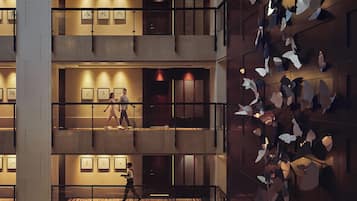 Experience the hotel's modern lobby with balconies, artwork, and a decorative screen.