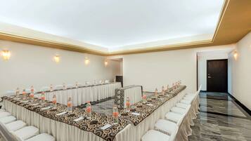 Un salón de conferencias con una larga mesa, sillas y botellas de agua.