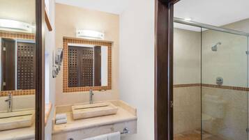 Un baño con un espejo grande, dos lavamanos, una ducha y una puerta de cristal.