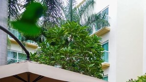 An outdoor dining area with a table set for two, surrounded by lush greenery and a pool. - Wyndham Merida (Mérida)