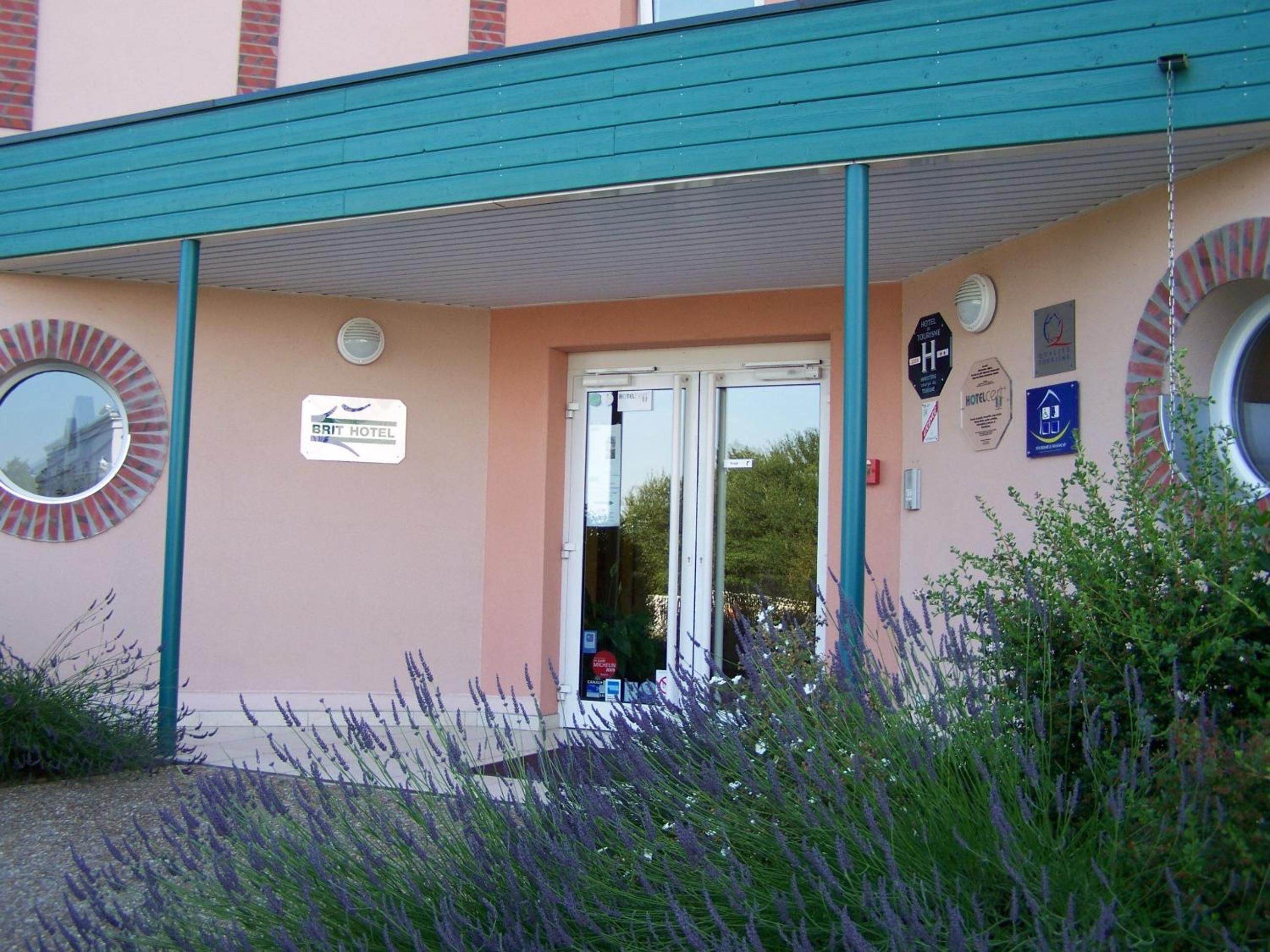 The Brit Hotel entrance with a teal awning, a signboard, and a circular window.