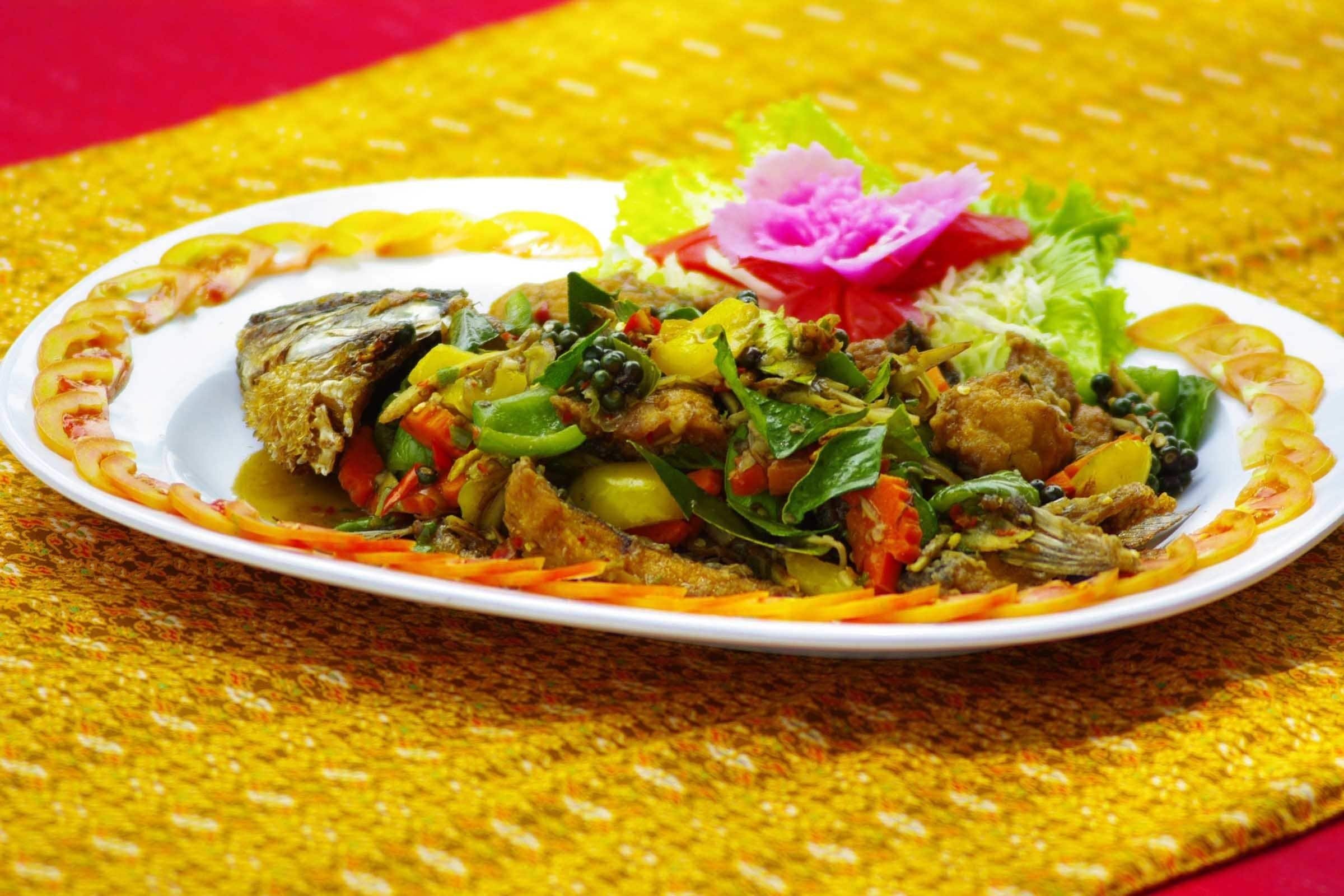 A plate of food with a decorative flower and a yellow patterned tablecloth.