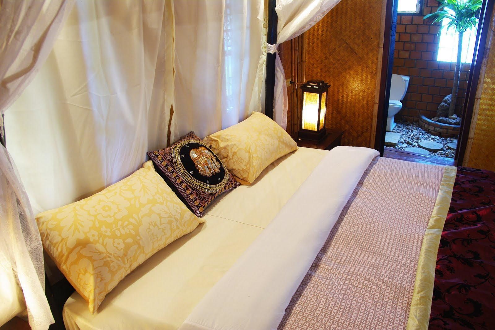 A bed with a canopy, a decorative pillow, and a nightstand with a lantern.
