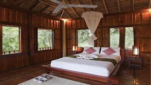 A wooden cabin bedroom with a bed, bedside tables, and a ceiling fan. - Zen Namkhan Boutique Resort (Luang Prabang)