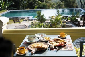 Une table à manger avec des aliments pour le petit-déjeuner et une vue sur une piscine.