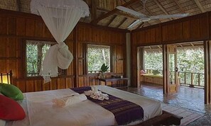 Une pièce en bois avec un lit, une fenêtre et un ventilateur de plafond.