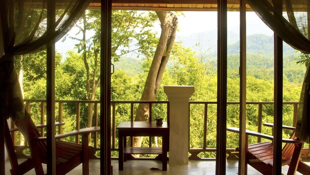 A wooden deck with a table and chairs, overlooking a lush green forest. - Zen Namkhan Boutique Resort (Luang Prabang)
