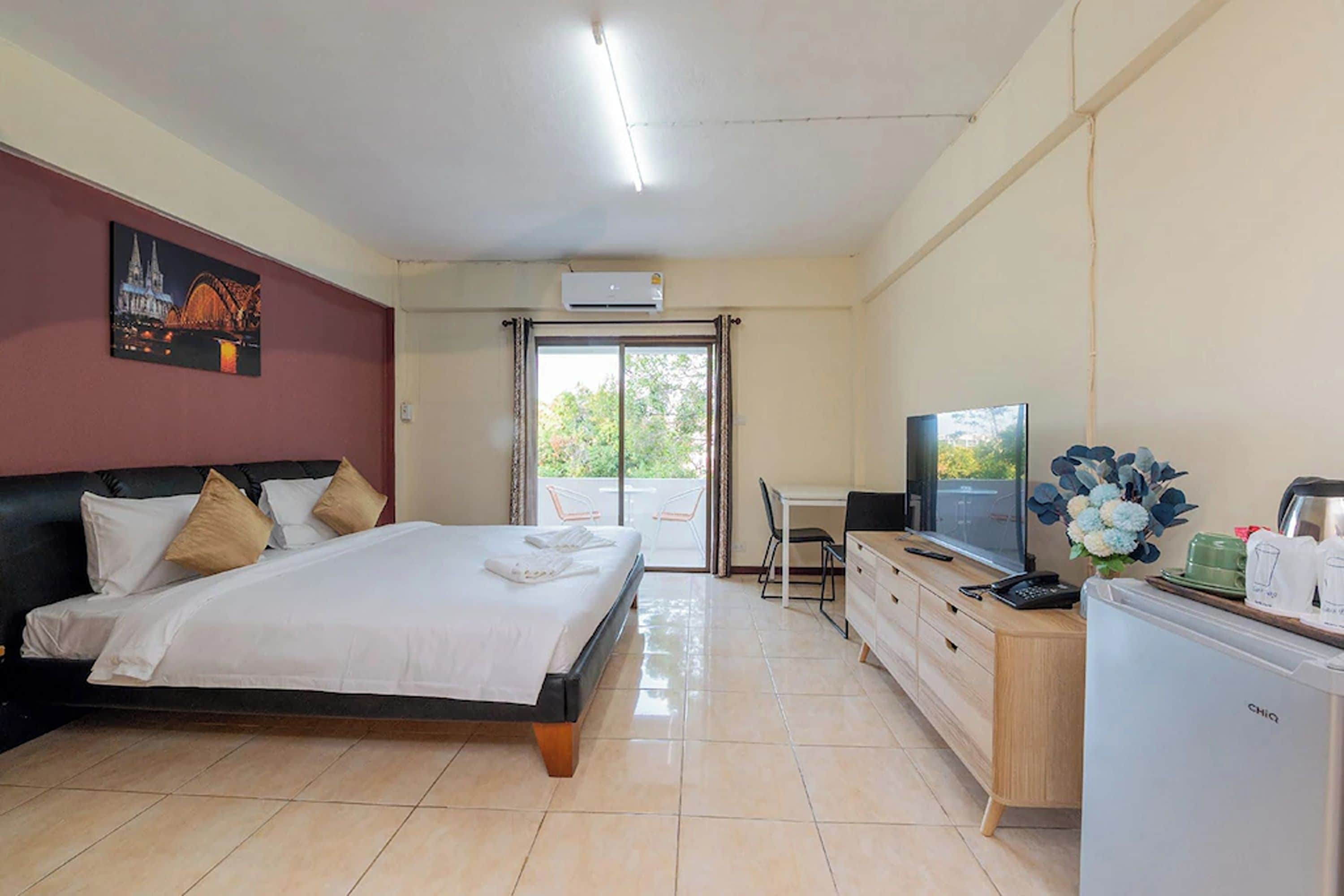 A hotel room with a bed, a desk, a television, and a view of the outdoors.