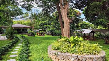 A well-maintained garden with a stone pathway, lush greenery, and wooden structures.