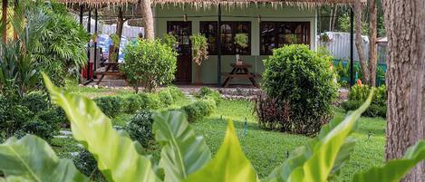 A traditional hut with a thatched roof, surrounded by lush greenery and a well-maintained garden.