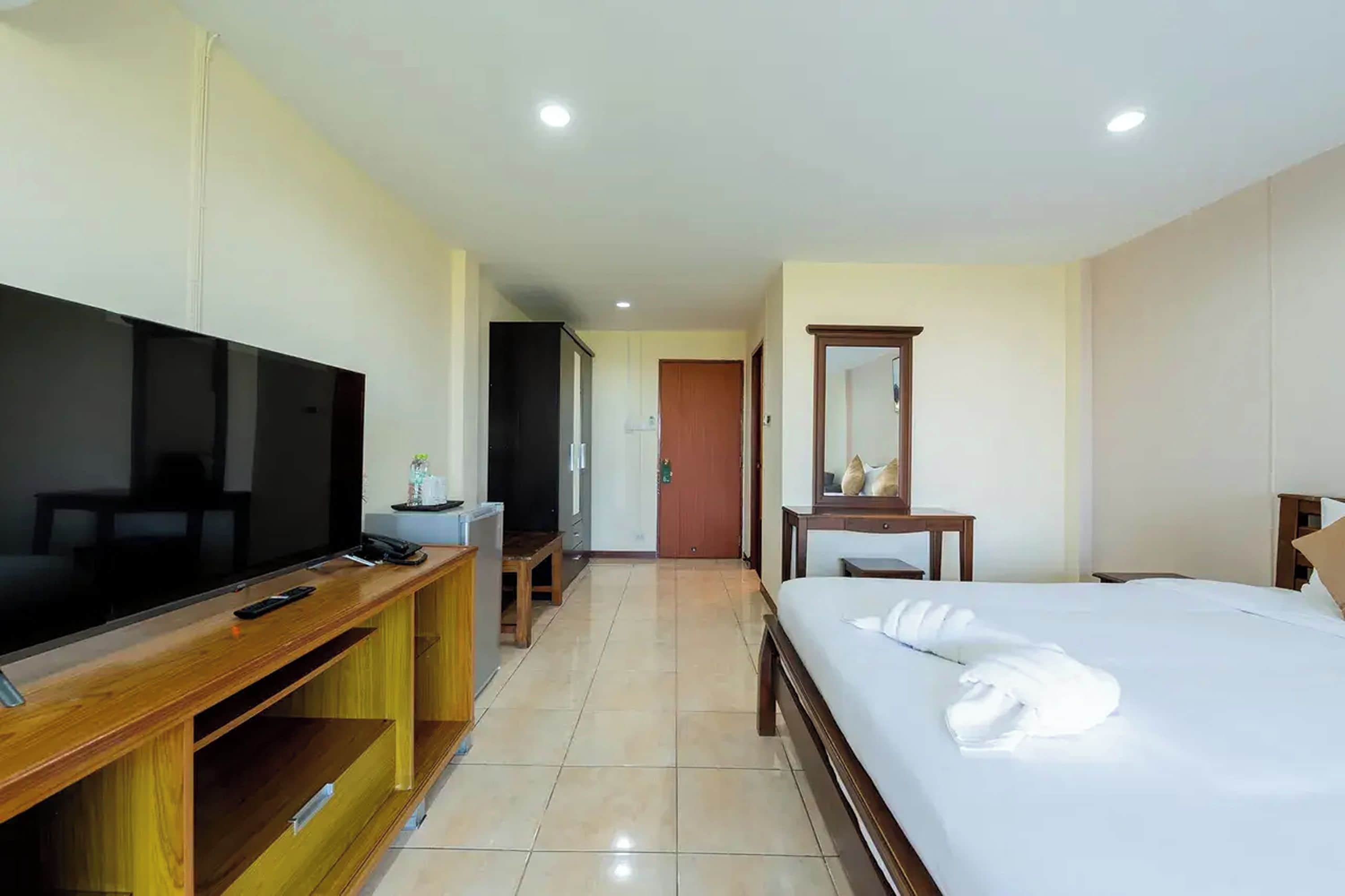 A hotel room with a bed, a TV, a desk, a chair, and a mirror.
