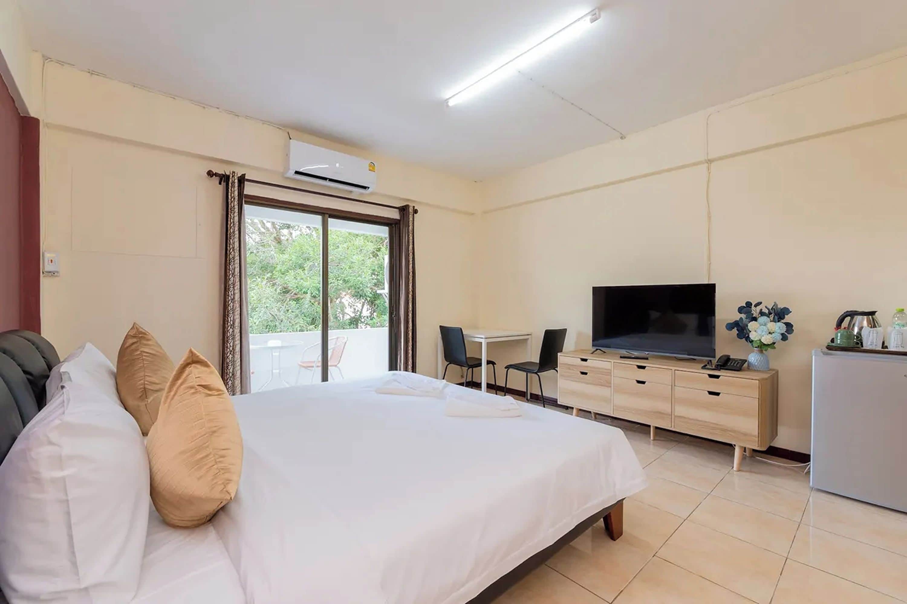 A hotel room with a bed, a desk, a television, and a kitchenette.