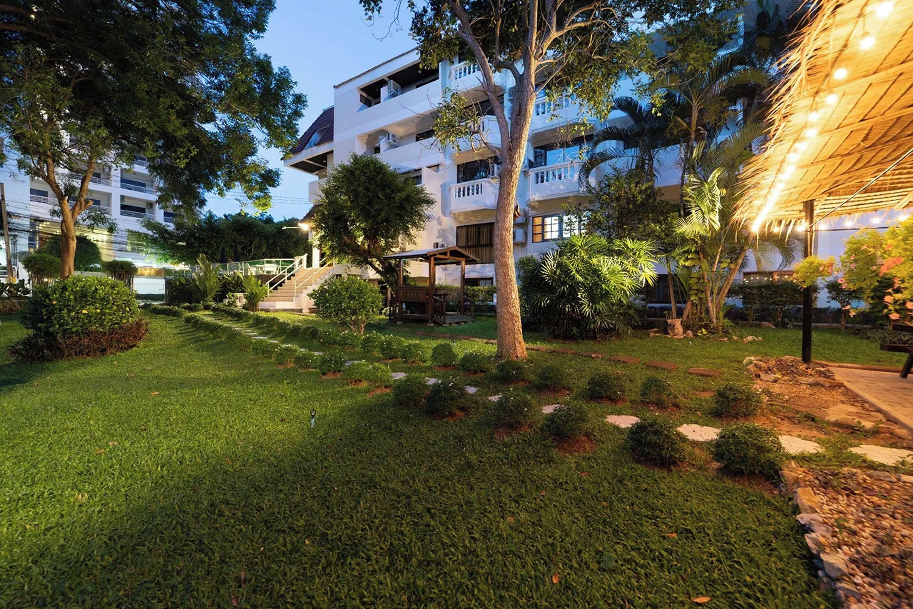 A well-maintained courtyard with a grassy area, trees, and a building with multiple balconies.