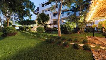 A well-maintained courtyard with a grassy area, trees, and a building with multiple balconies.