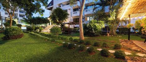 A well-maintained courtyard with a grassy area, trees, and a building with multiple balconies.