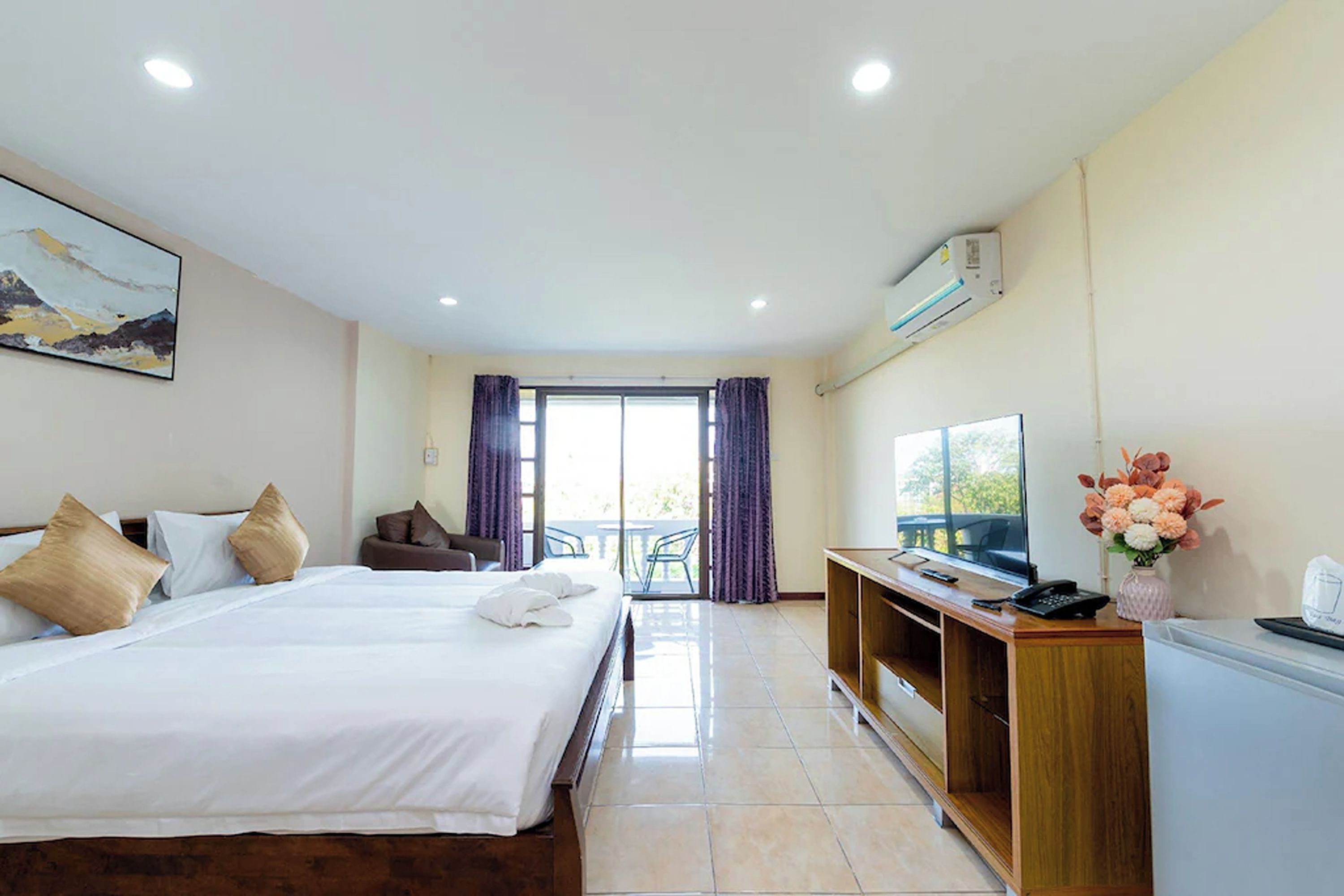 A hotel room with a large bed, a desk with a computer, a TV, and a view of the outdoors.