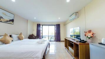 A hotel room with a large bed, a desk with a computer, a TV, and a view of the outdoors.