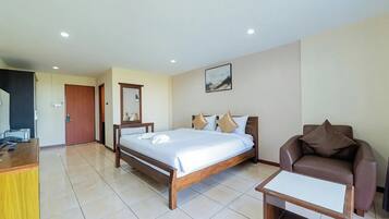 A hotel room with a bed, a chair, a desk, and a door.