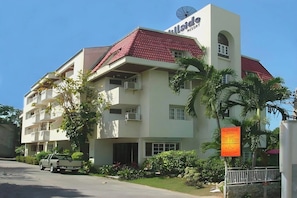 A multi-story hotel with a red roof, balconies, and a sign indicating it's a resort. - Hillside Resort (Pattaya)