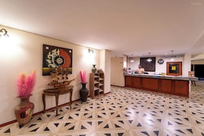 A reception area with a patterned floor, a reception desk, and decorative vases.