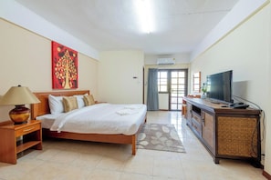 A hotel room with a bed, a television, a desk, and a painting on the wall. - Hillside Resort (Pattaya)