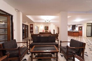 A living room with a sofa set, a coffee table, and a dining area with a chandelier. - Hillside Resort (Pattaya)