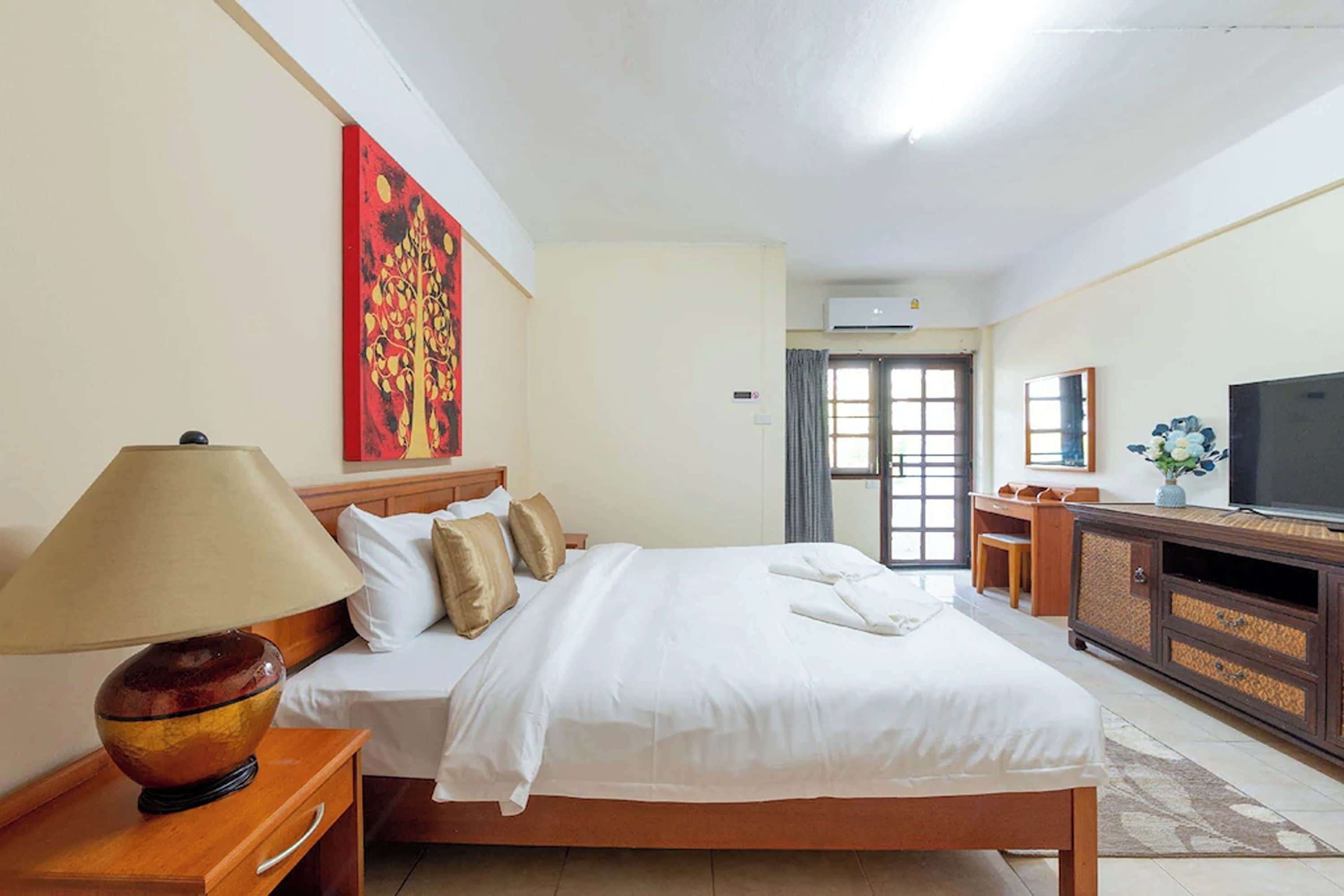 A hotel room with a bed, a desk, a television, and a large window.
