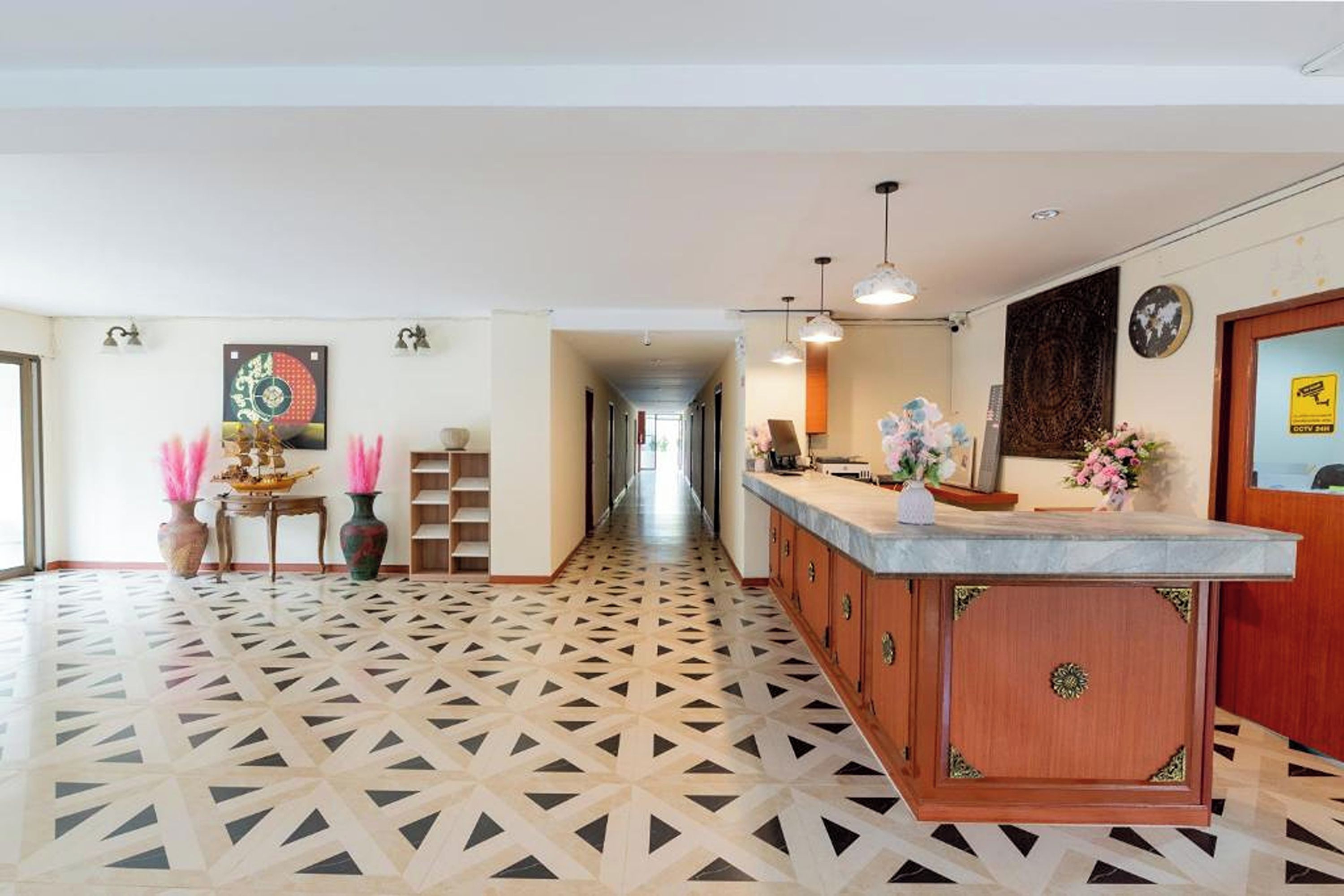 A hotel lobby with a reception desk, patterned floor, and decorative vases.