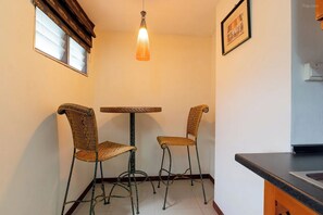 A small kitchen with a dining table and two chairs, a hanging light fixture, and a framed picture on the wall. - Hillside Resort (Pattaya)