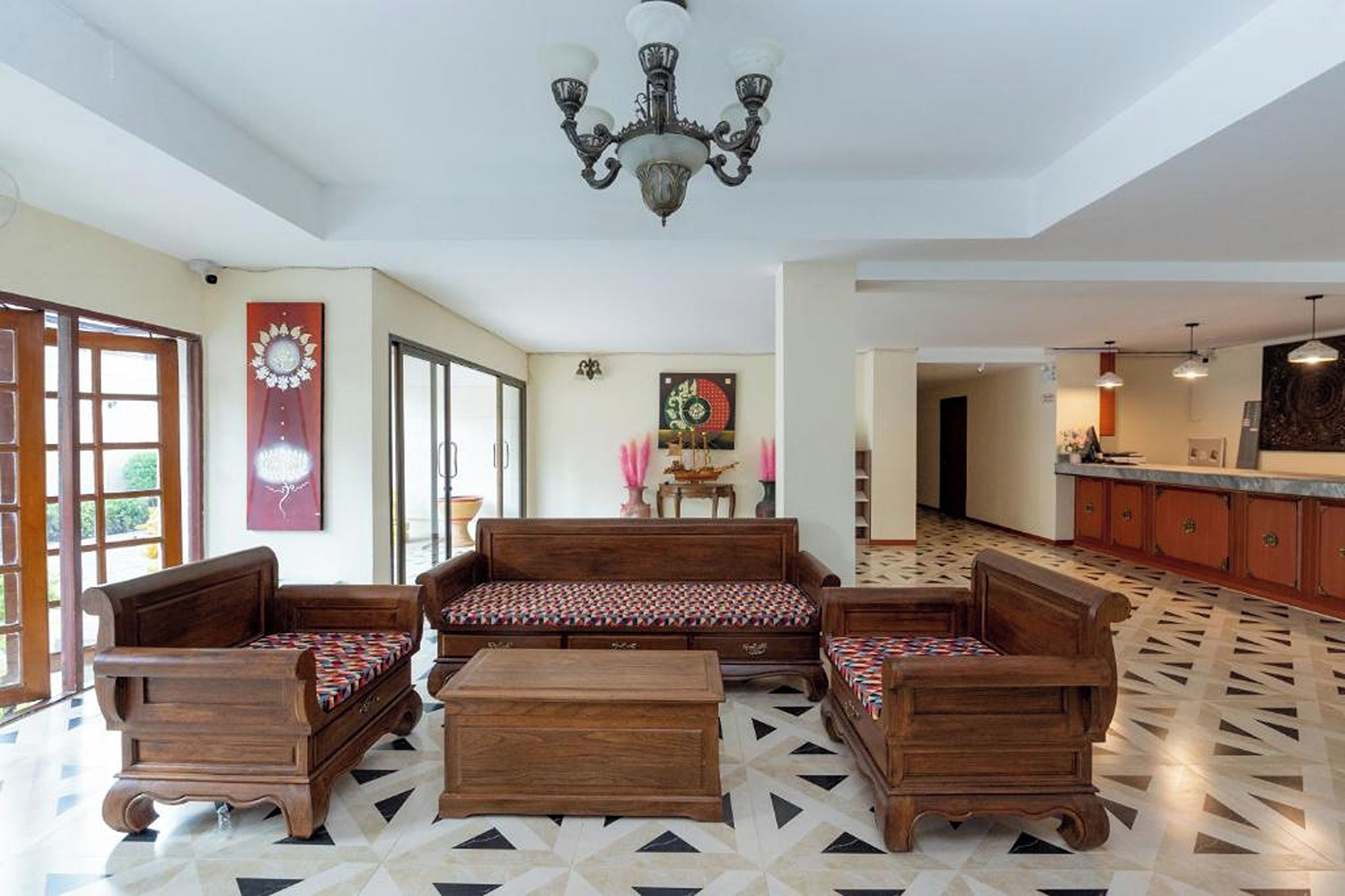 A spacious living area with a patterned floor, a wooden sofa set, and a chandelier.