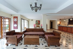 A spacious living area with a patterned floor, a wooden sofa set, and a chandelier.