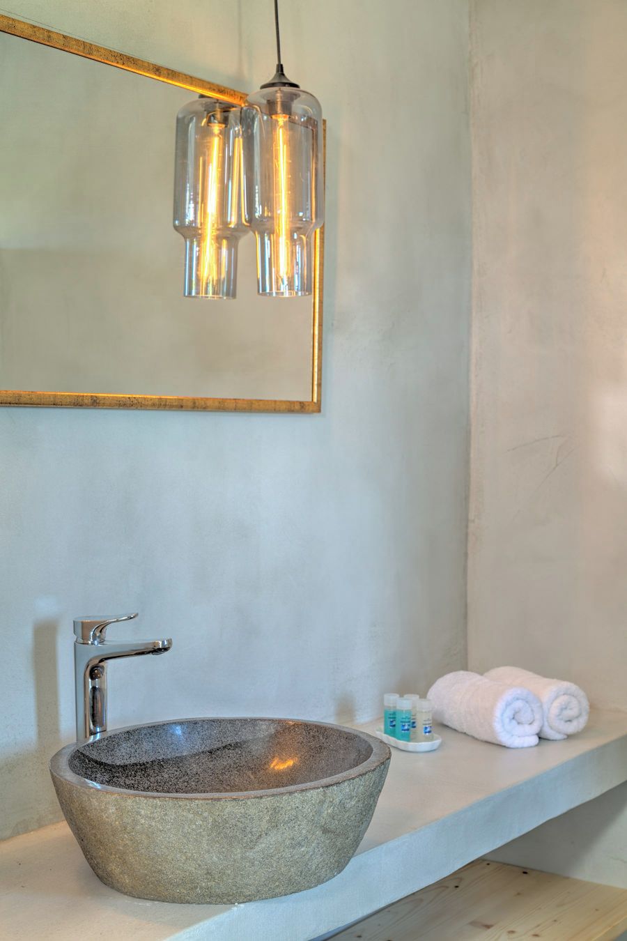 A bathroom with a stone sink, a mirror, and a towel rack.