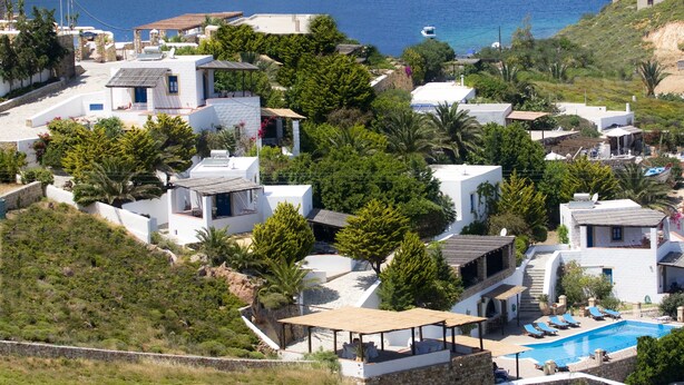 A coastal residential area with modern houses, a swimming pool, and a view of the sea.
