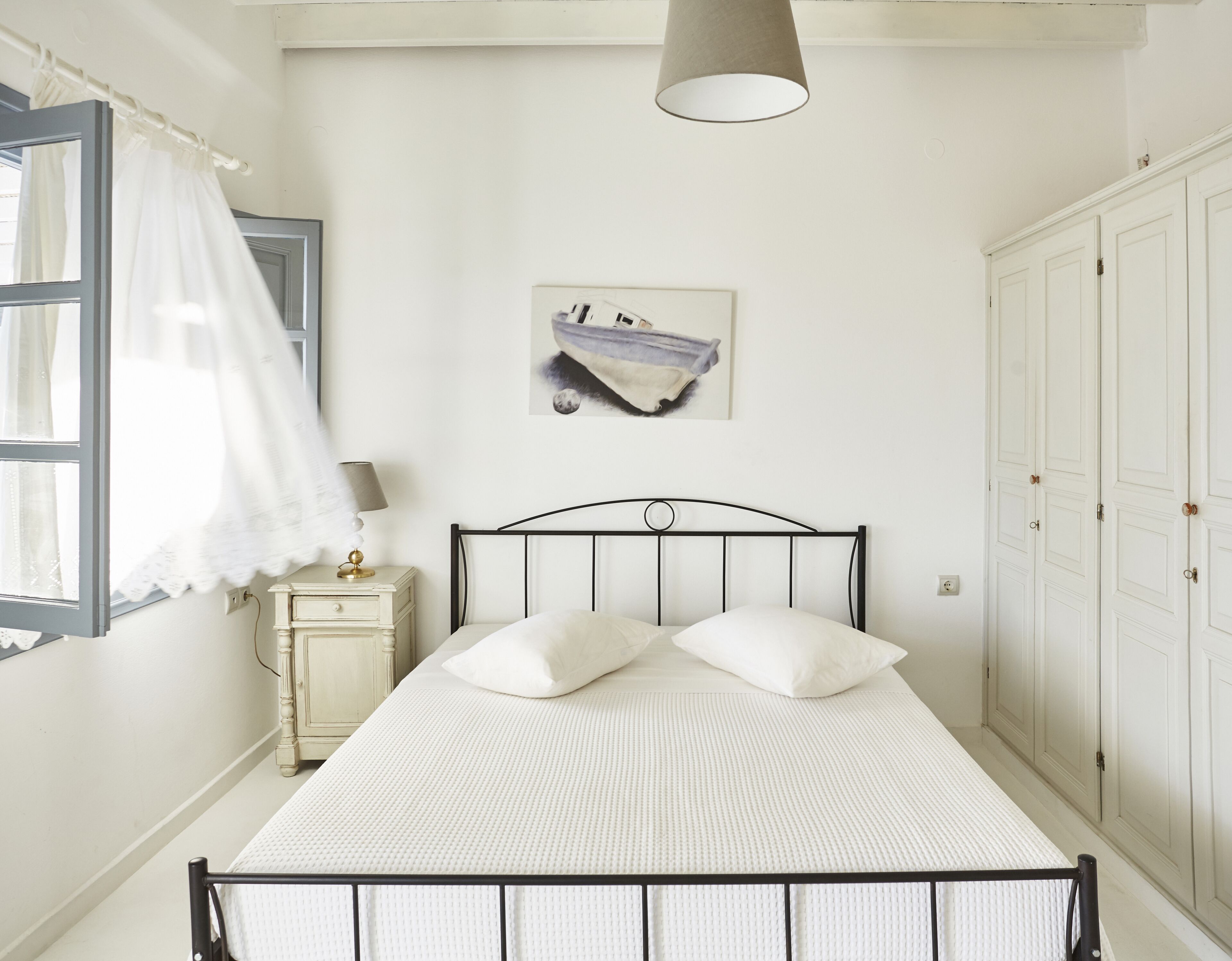 Ein Schlafzimmer mit einem Bett, einem Nachttisch, einer Lampe, einem Gemälde und einem Kleiderschrank.
