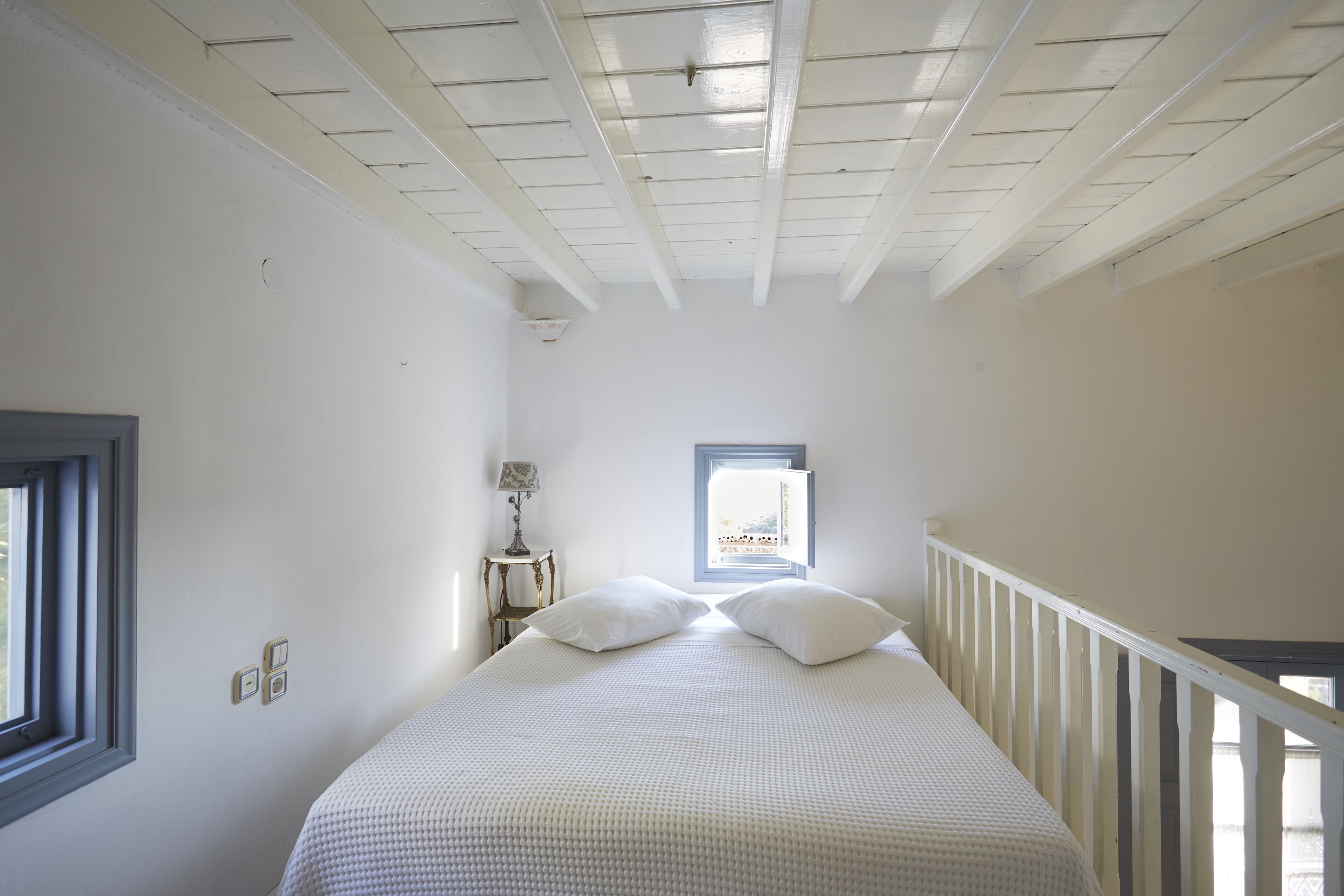 A bedroom with a bed, a window, and a nightstand.