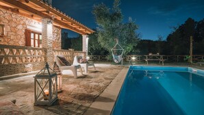 A stone building with a pool, outdoor seating, and hanging chairs. - Alegria Villas (Zakynthos)