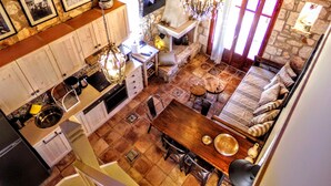 A spacious kitchen with a dining area, stone walls, and a fireplace. - Alegria Villas (Zakynthos)