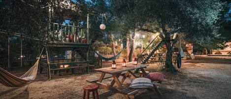 A wooden deck with a hammock, picnic table, and benches.