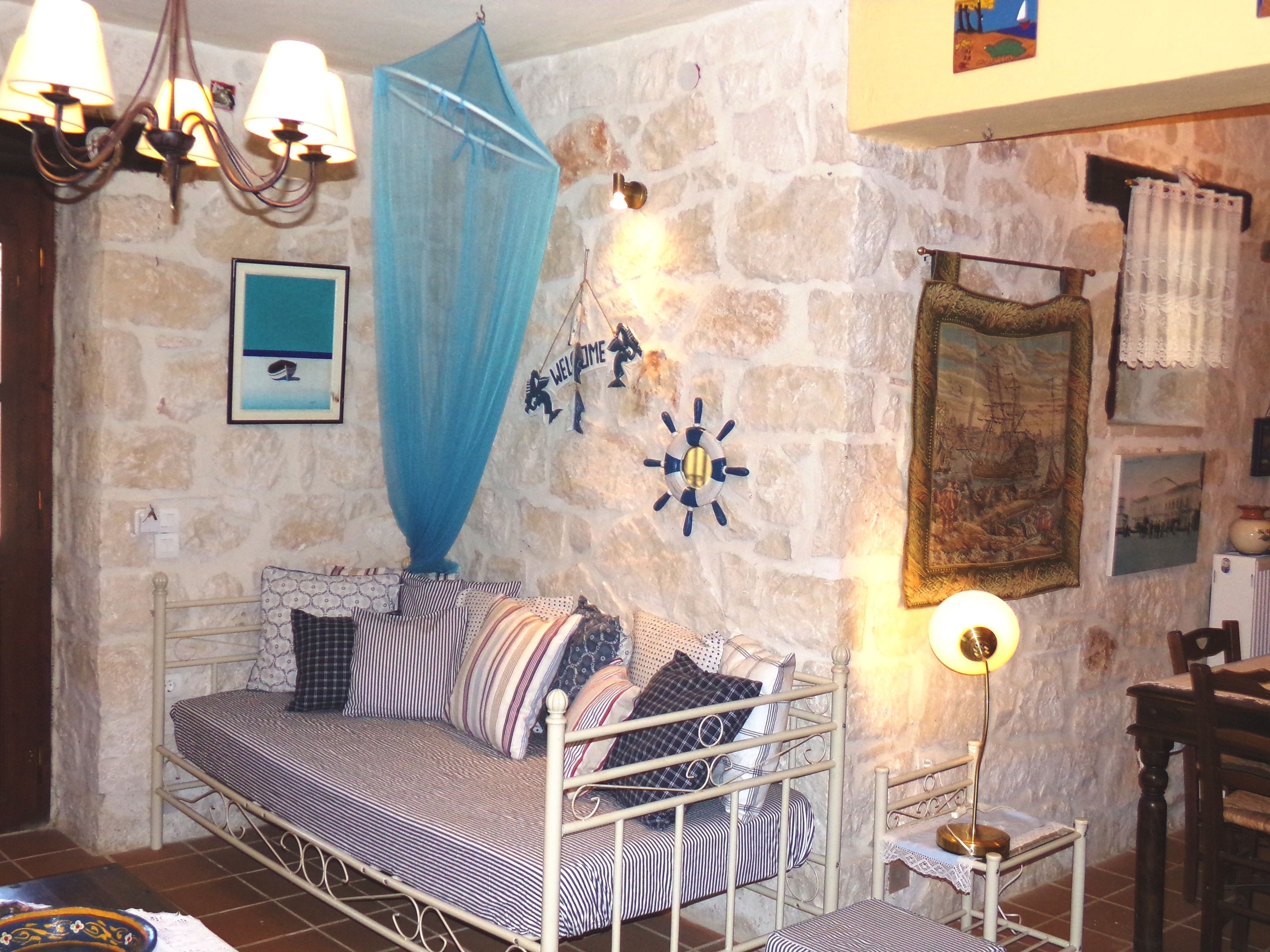 A cozy room with a metal bed, a blue canopy, a 'Welcome' sign, a life preserver decoration, and a framed painting on the wall.