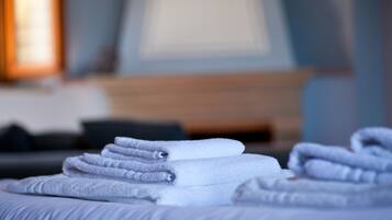 A neatly folded stack of white towels on a bed in a hotel room.