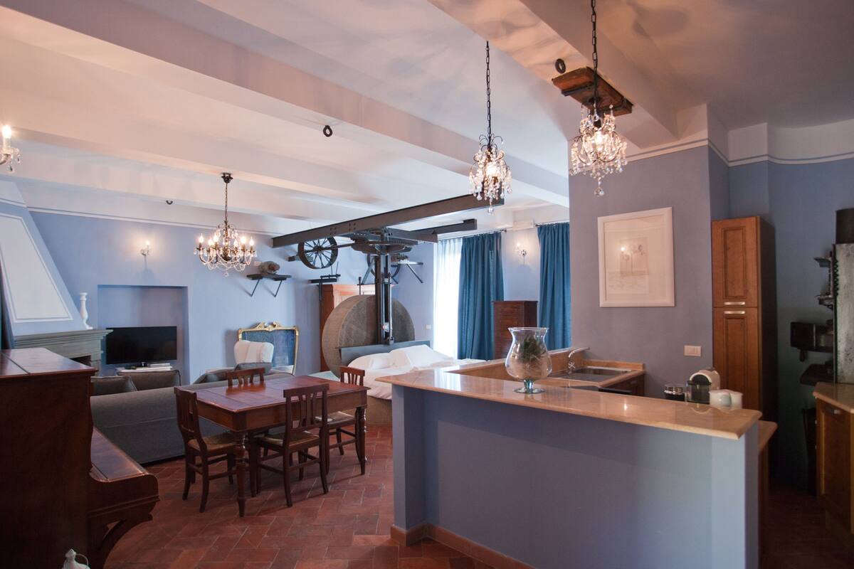 A spacious kitchen with a central island, wooden furniture, and pendant lighting.
