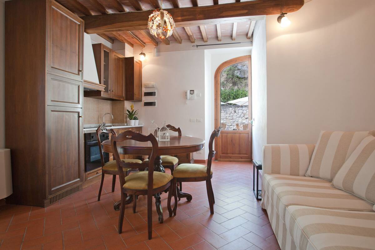 A kitchen with wooden cabinets, a dining table with chairs, and a sofa.