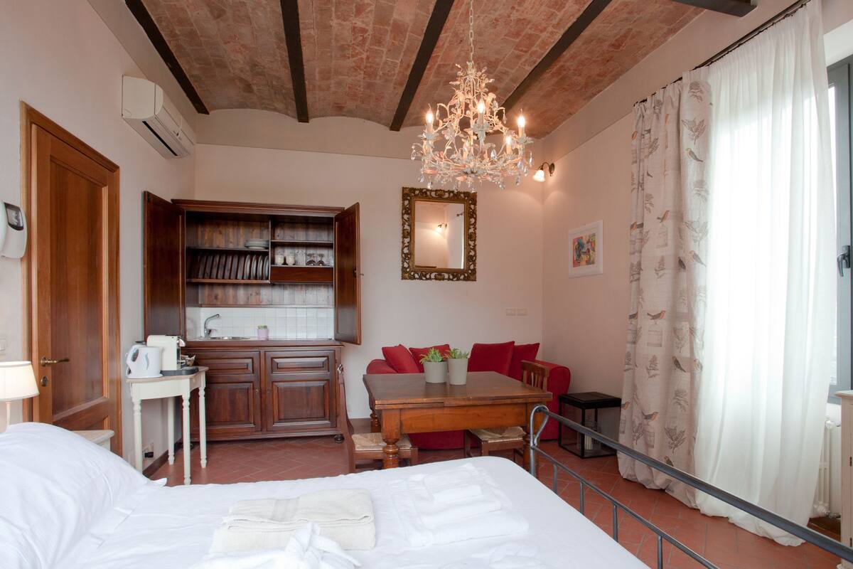 A hotel room with a bed, a dining table, a kitchen area, and a living space.