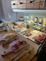 Un bufé con una variedad de alimentos, incluyendo quesos, carnes y salsas.