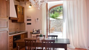 A kitchen with wooden cabinets, a dining table with chairs, a chandelier, and a view of the outdoors through a glass door. - Relais Villa Belvedere (Figline e Incisa Valdarno)