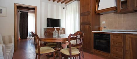 Un comedor con una mesa y sillas de madera, un televisor y una cocina con gabinetes de madera.