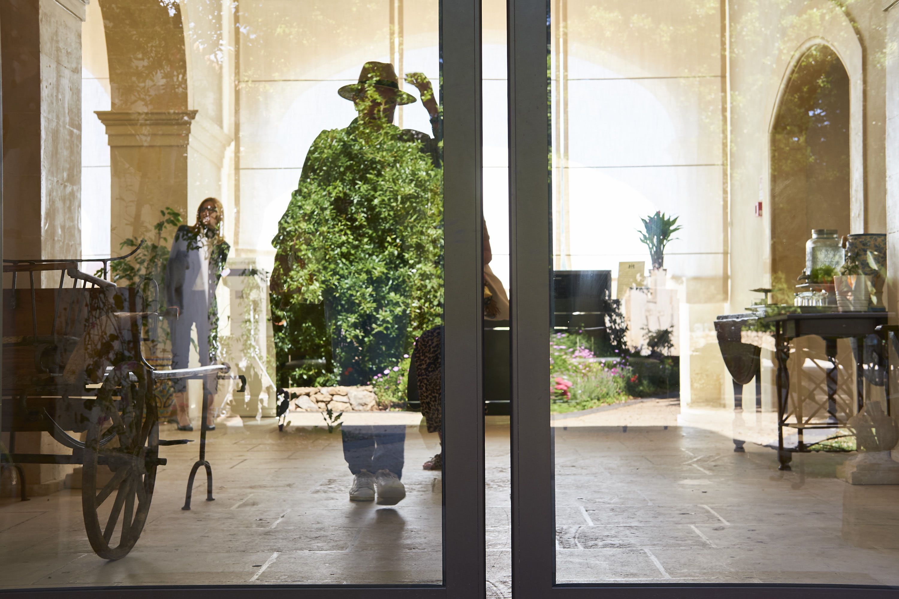A courtyard with a statue, a bicycle, and a table with a potted plant.