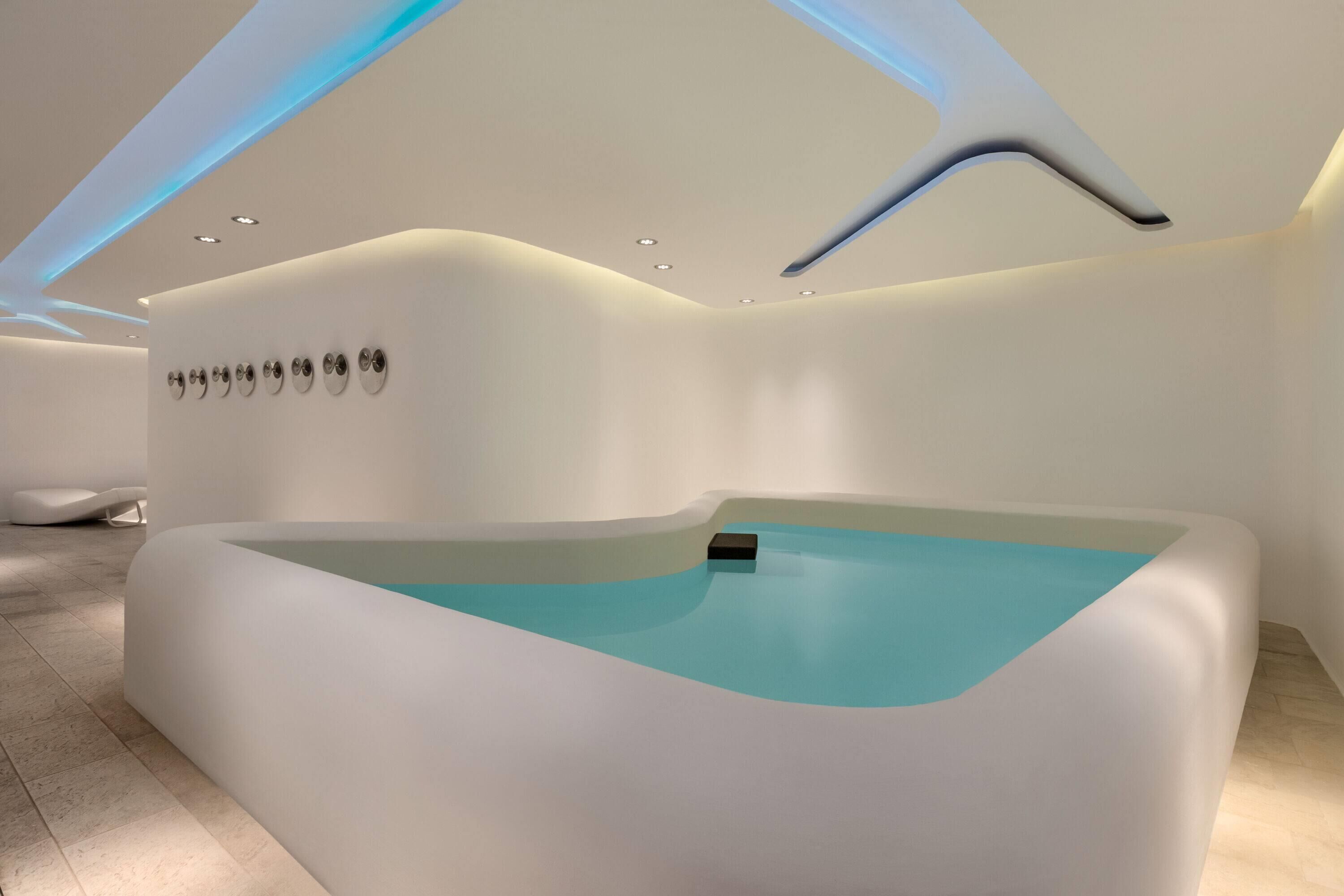 Una moderna stanza spa con un design di piscina originale, illuminazione a incasso ed estetica minimalista.