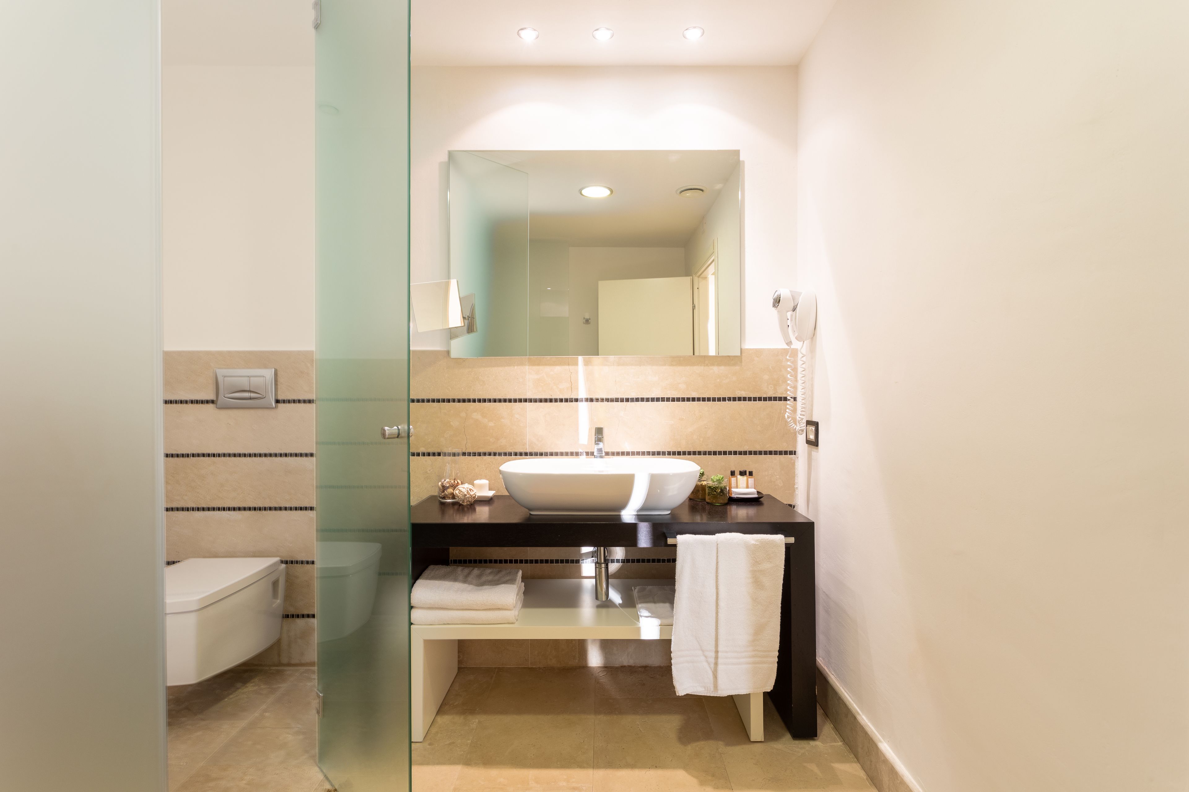 A modern bathroom with a glass shower enclosure, a white sink, and a large mirror above it.