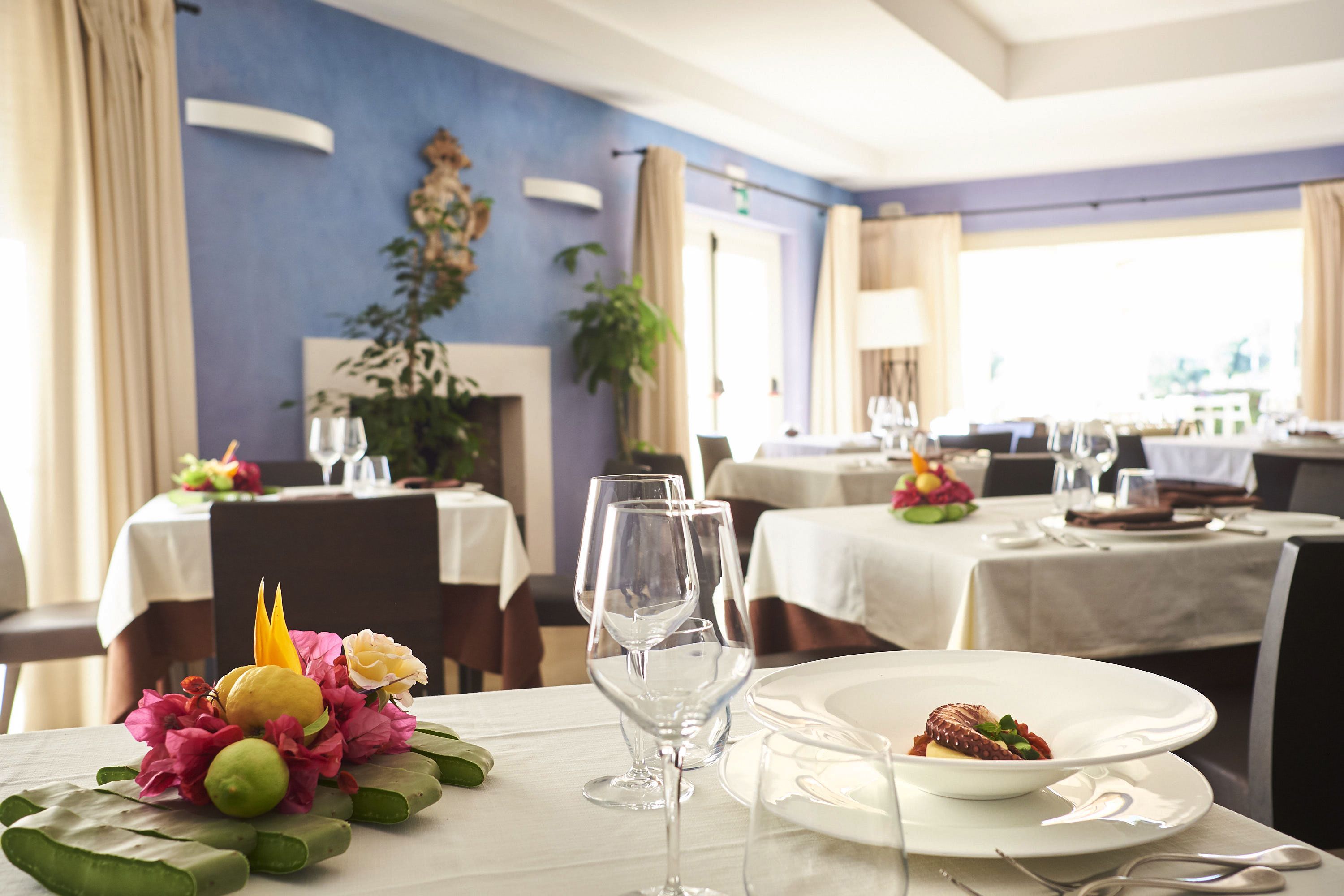 A dining area with tables set for a meal, clear glassware, and a decorative centerpiece.